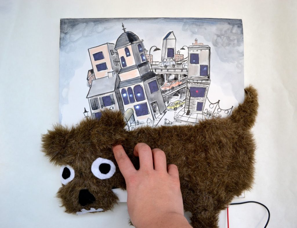 A hand illustrated city has been drawn on top of a brown dog with fake fur and a hand it stroking it.