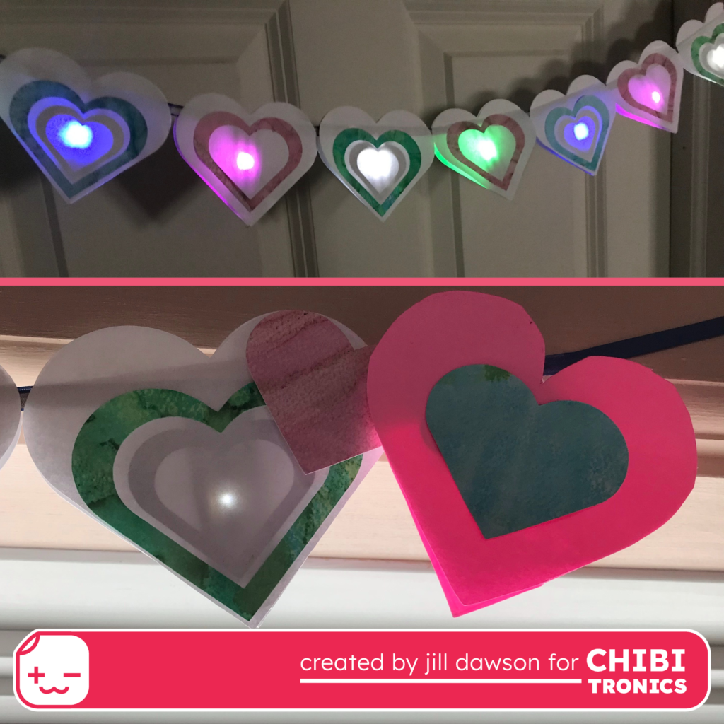 Two part image

Top:  Seven white paper hearts are draped over a ribbon in front of a white door.  Each heart has a glowing light in the center.

Bottom:  Two large paper hearts are attached to a ribbon.  The one on the left is white and has a white light in the center.  The one on the right is pink with a blue paper center.