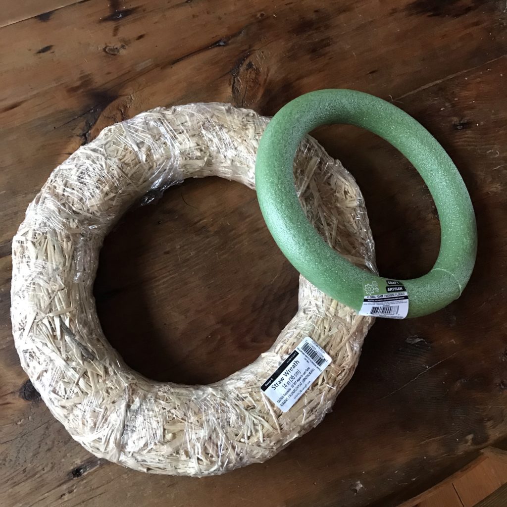 A large straw wreath form sits to the left of smaller, green, foam wreath form