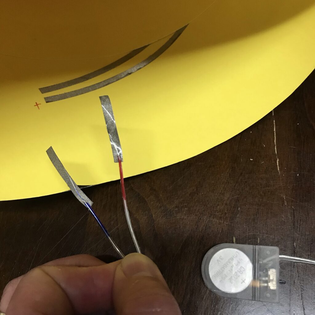 strips of conductive fabric tape added to the leads of a battery holder