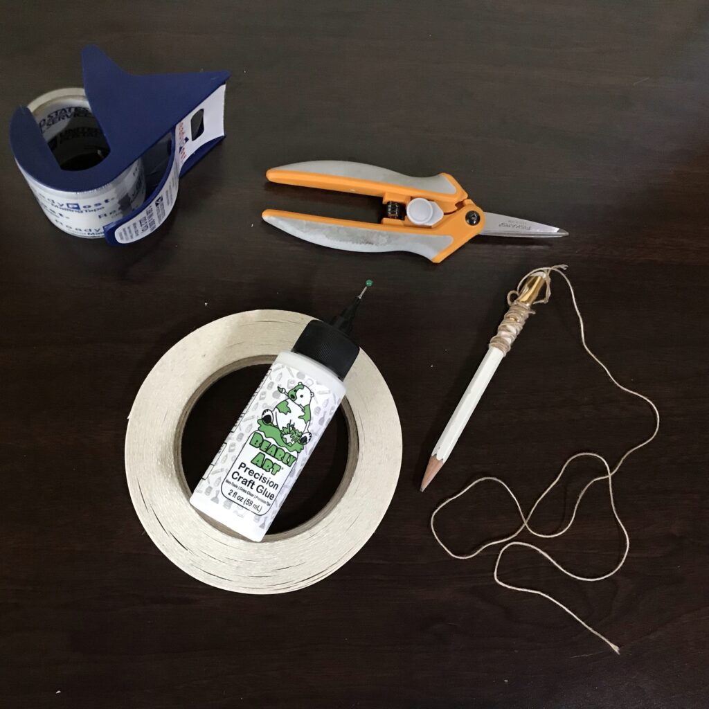 Roll of tape, scissors, glue, and a pencil on a string