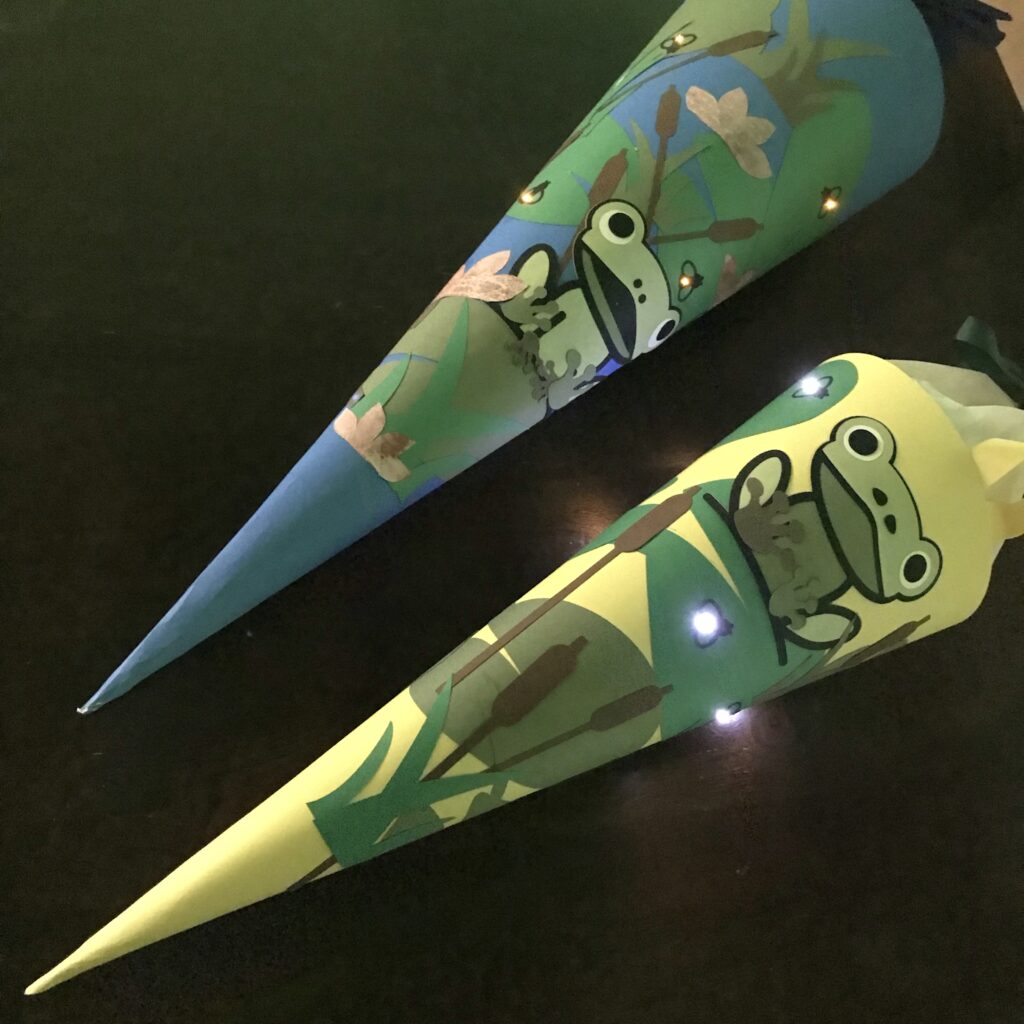 Two Schultüte (school cones with frogs and glowing fireflies