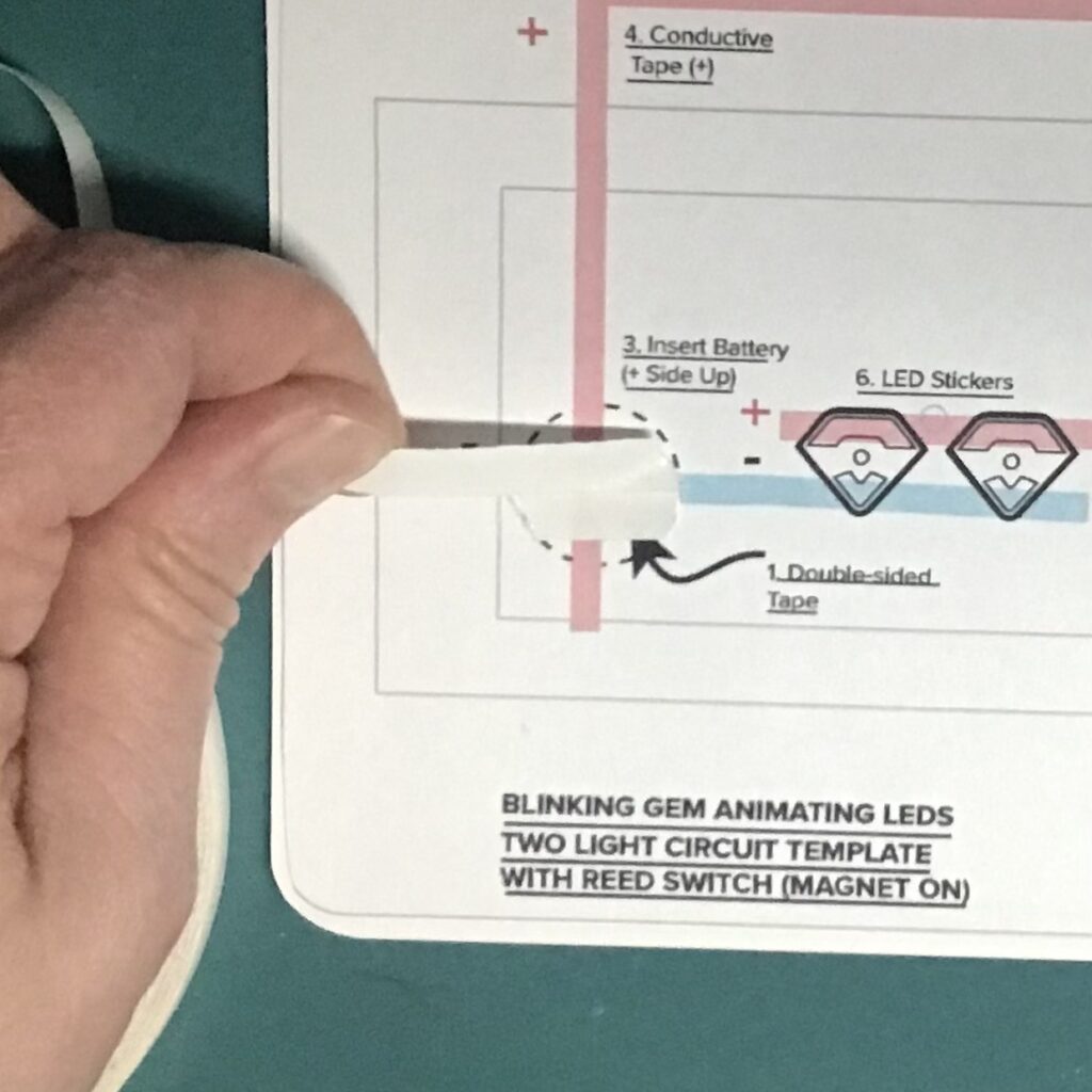 Two pieces of double-sided tape are placed in the round footprint denoting where a coin cell battery will be placed.